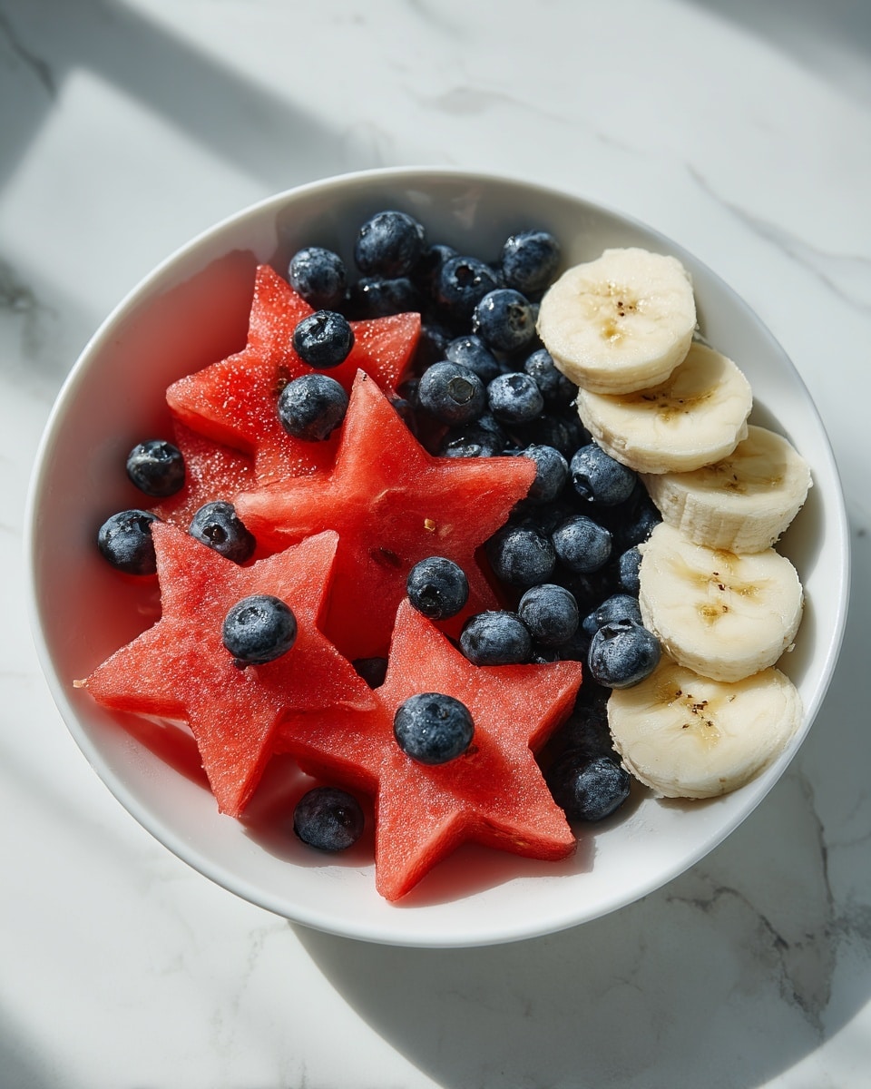 A white bowl sits on a white marbled surface, filled with three types of fruit arranged in layers. The bottom layer is cut into star shapes from watermelon, showing a bright red color with a smooth texture and small black seeds. Scattered on the watermelon stars are round, deep blue blueberries that add a smooth and slightly shiny contrast. On one side of the bowl, there is a group of round banana slices placed on top, showing a pale yellow color with a soft texture and small brown dots in the center. Some blueberries are also placed on the banana slices, mixing the colors with the red watermelon base. The light shines clearly on the bowl, highlighting the fresh and bright colors of the fruit photo taken with an iphone --ar 4:5 --v 7
