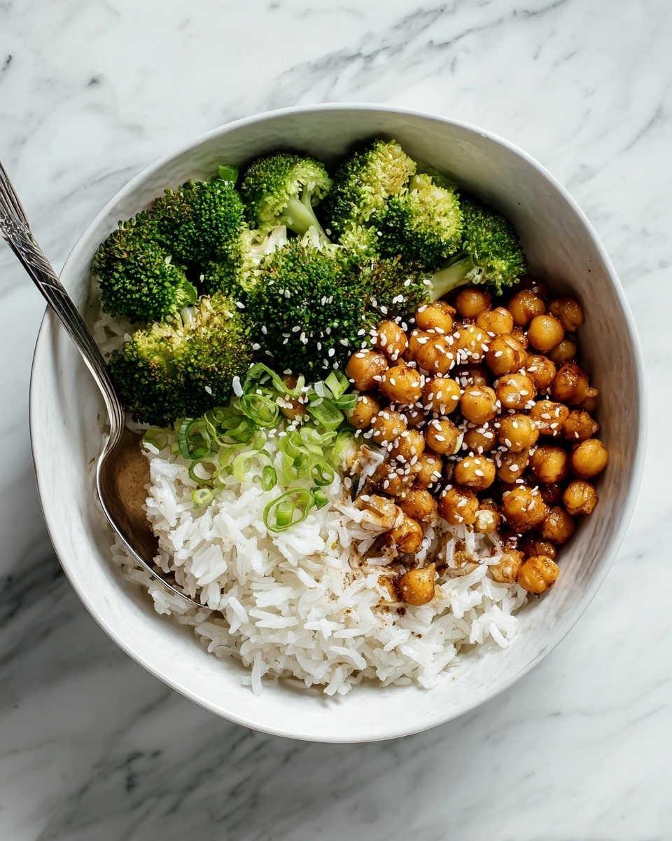 A white bowl on a white marbled surface holds three distinct layers: the bottom layer is soft, fluffy white rice; the middle layer is a serving of shiny, golden-brown chickpeas coated in a slightly glossy sauce, sprinkled with sesame seeds and small red chili flakes; the top layer consists of bright green broccoli florets with a slightly rough texture. A silver fork rests inside the bowl on the left side. The overall look is fresh and colorful, with the rice contrasting the warm chickpeas and vibrant broccoli. Photo taken with an iphone --ar 4:5 --v 7